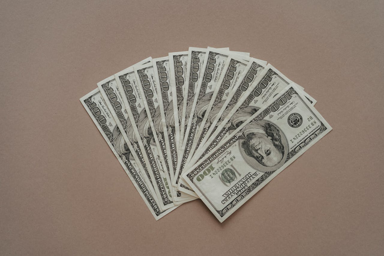 A neat arrangement of US dollar banknotes laid out in a fan shape on a brown surface.